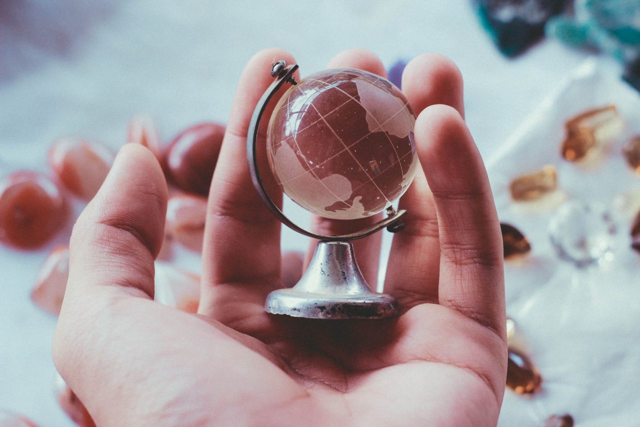 A hand cradles a tiny globe.