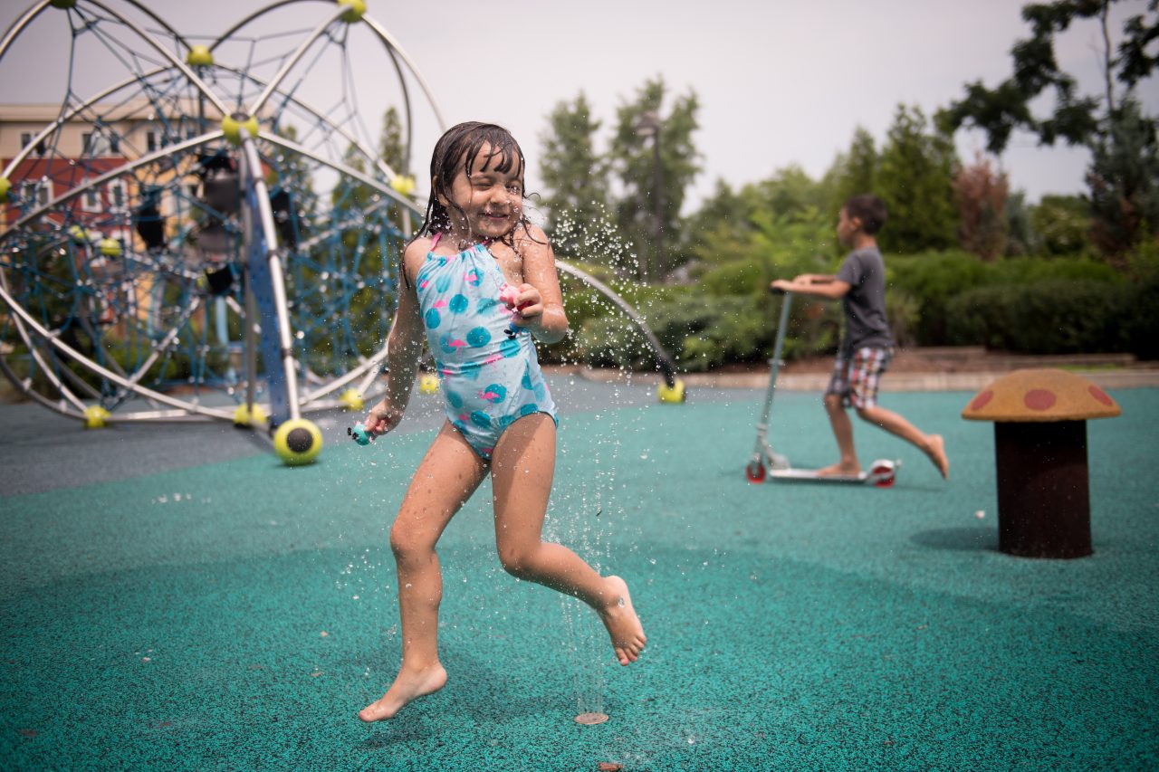 Julia Ferreira, 4, plays in the fountains at Creekside Common Park, which includes a year-round skating rink, a motor & sensory skill park, and water fountains for play.  (AEM Chelsea, Mass. slideshow image)